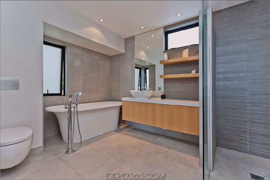 Modernes Badezimmer mit einer freistehenden Badewanne, die mit Steinfliesen verkleidet ist